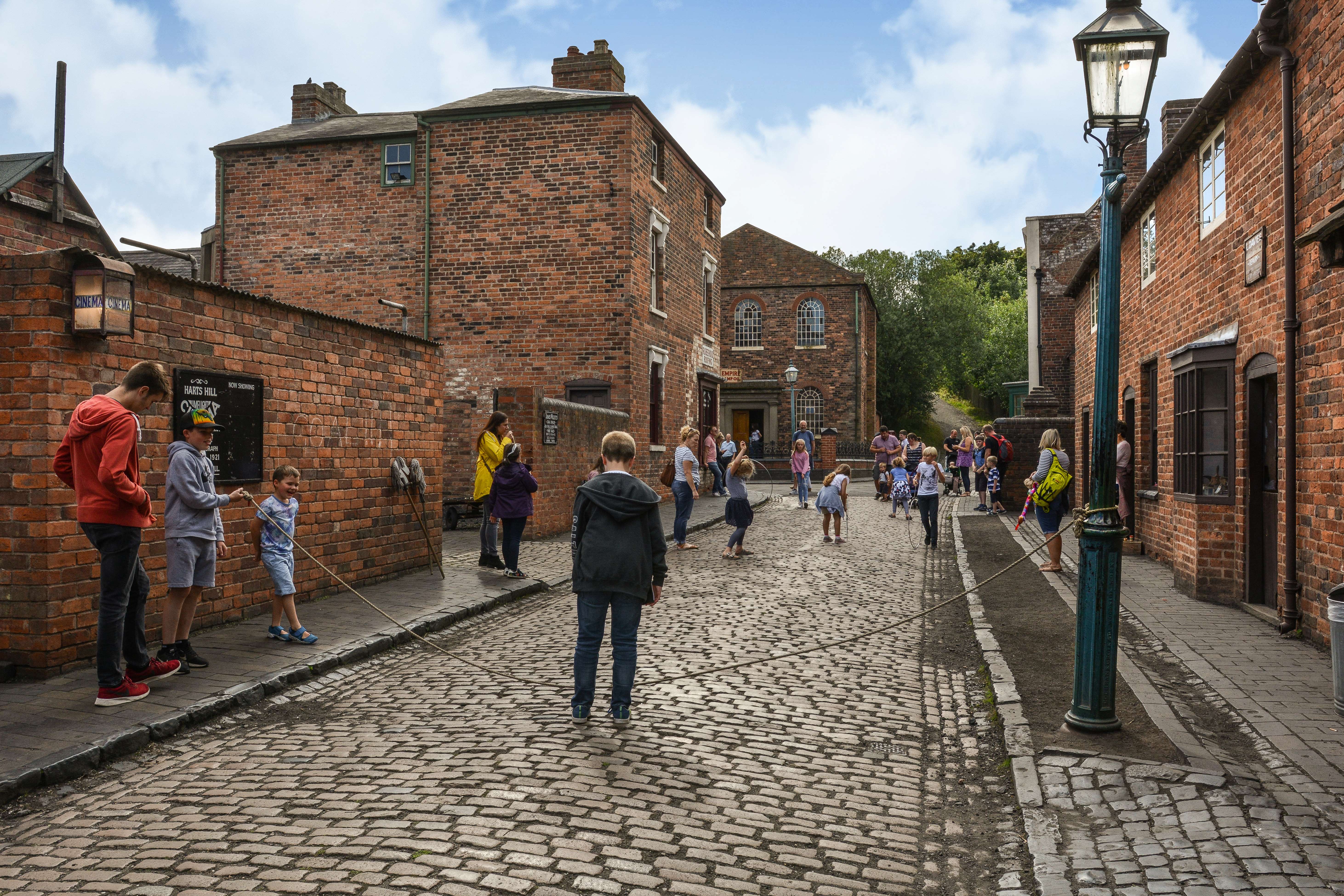 People standing in a street at a living museum, playing old fashioned games