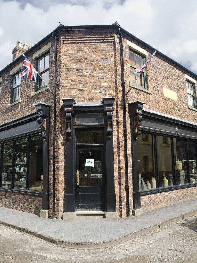 Strada con edifici in mattoni e bandiera britannica, con negozio all'angolo.