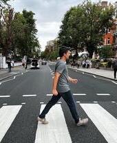 Un uomo che attraversa la strada fuori dagli Abbey Road Studios, una riproduzione della famosa copertina dell'album dei Beatles