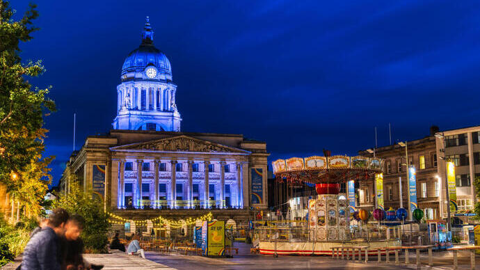 Evening view of city square with large municipal building and a merry go round.