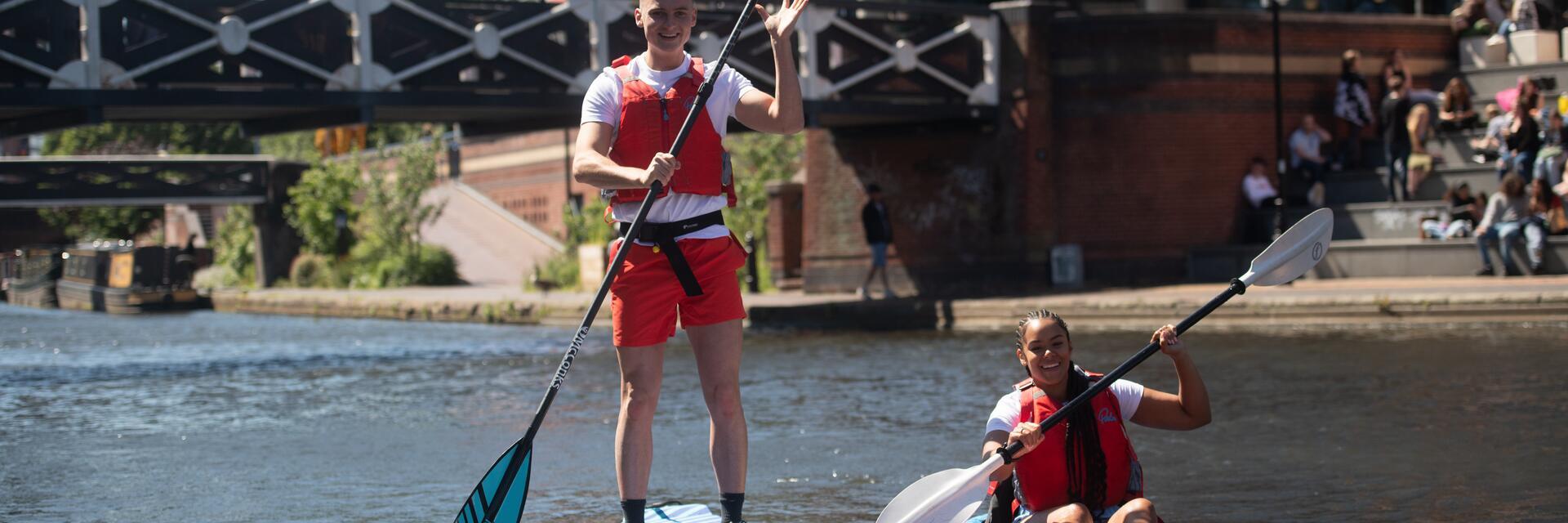 Two men kayaking on canal through central Birmingham