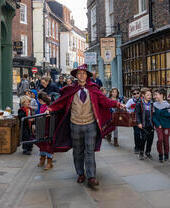 Ein kostümierter Führer in einem Zauberer-Outfit, der durch die Straßen läuft, Teil des Wizard Walk of York, North Yorkshire