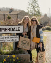 Two people posing outside the Emmerdale sign on a tour