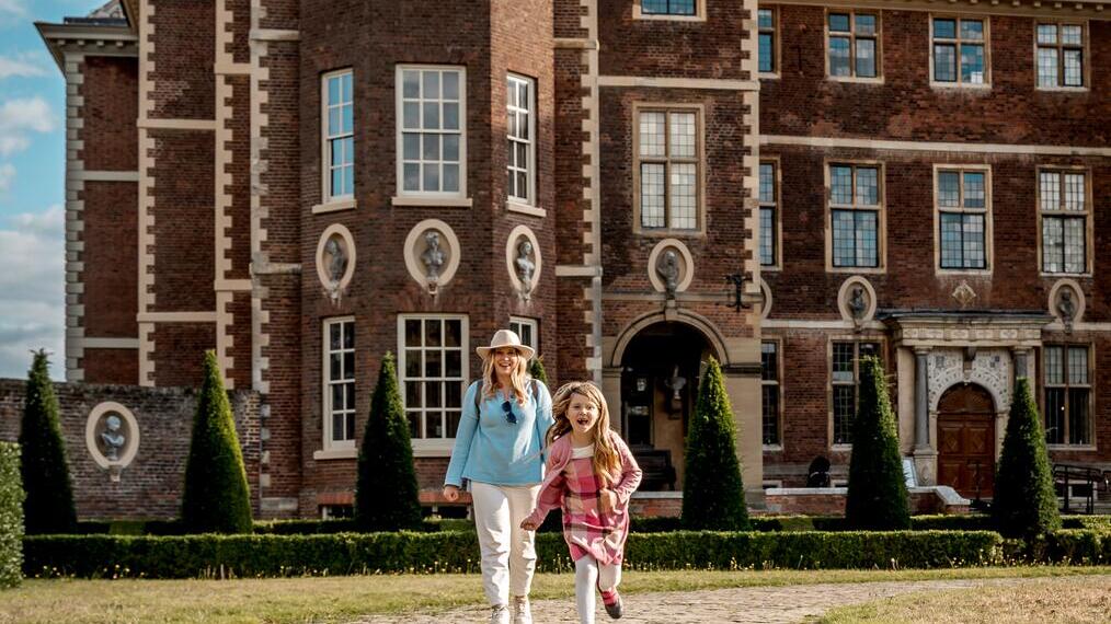 Una madre camina y su hija corre delante de Ham House.