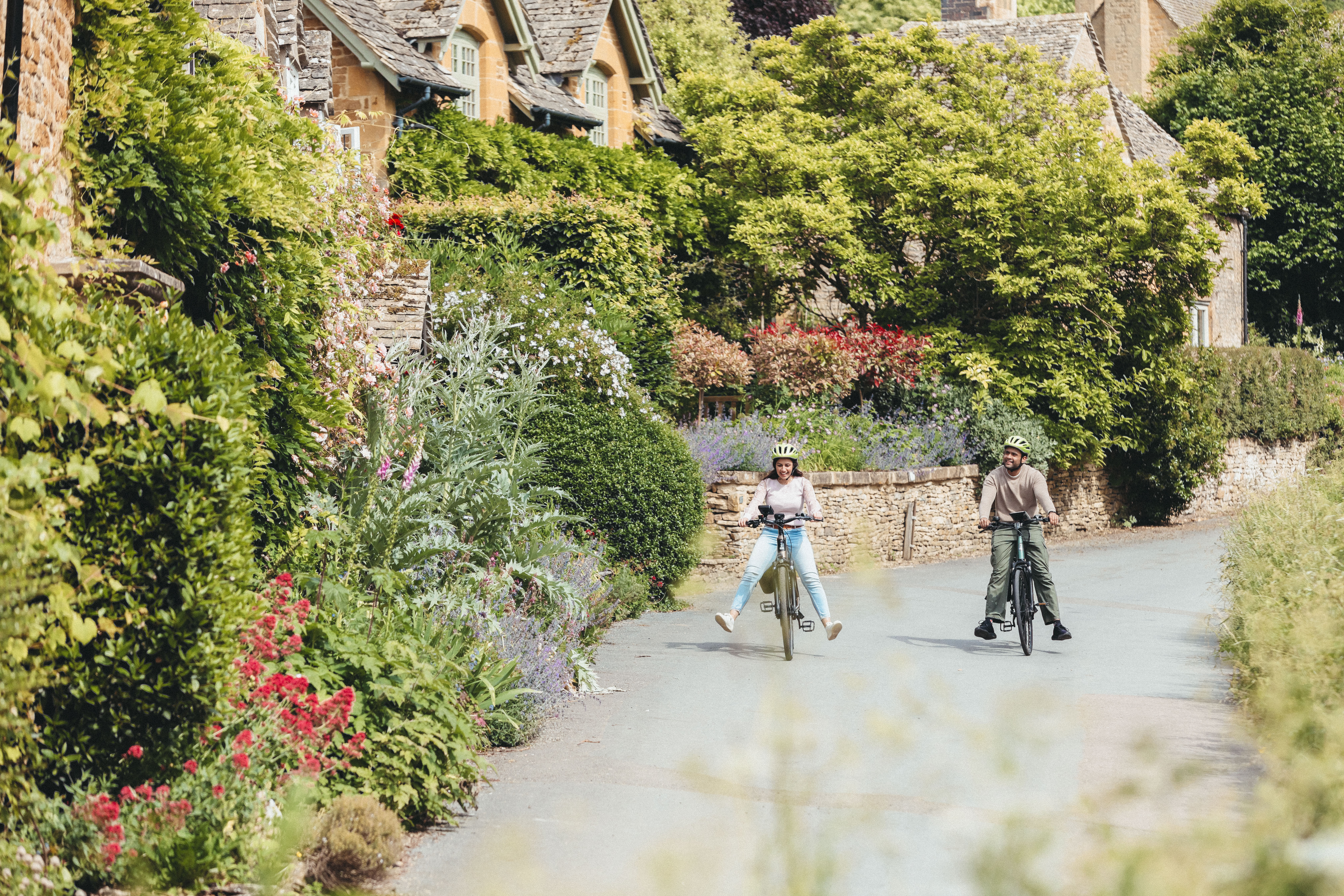 A man and and woman cycle through a quaint village