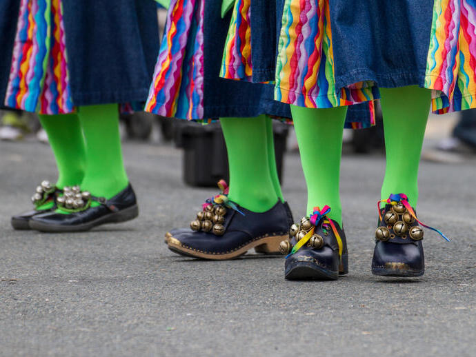 People in green tights and black shoes dancing at a folk festival.