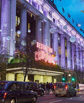 A large department store decorated with Christmas lights on a busy street