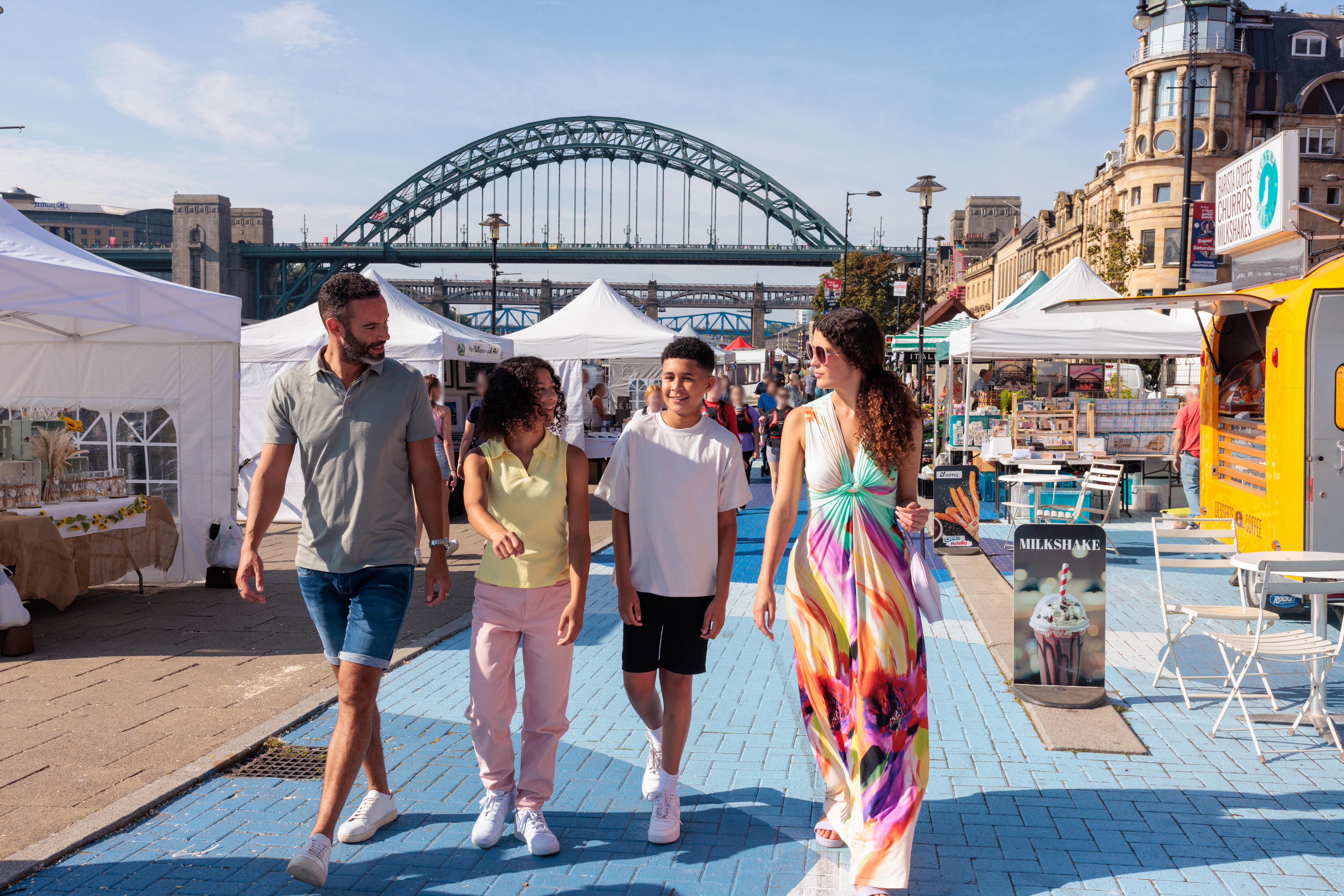 Family walking through stalls at a market in a city