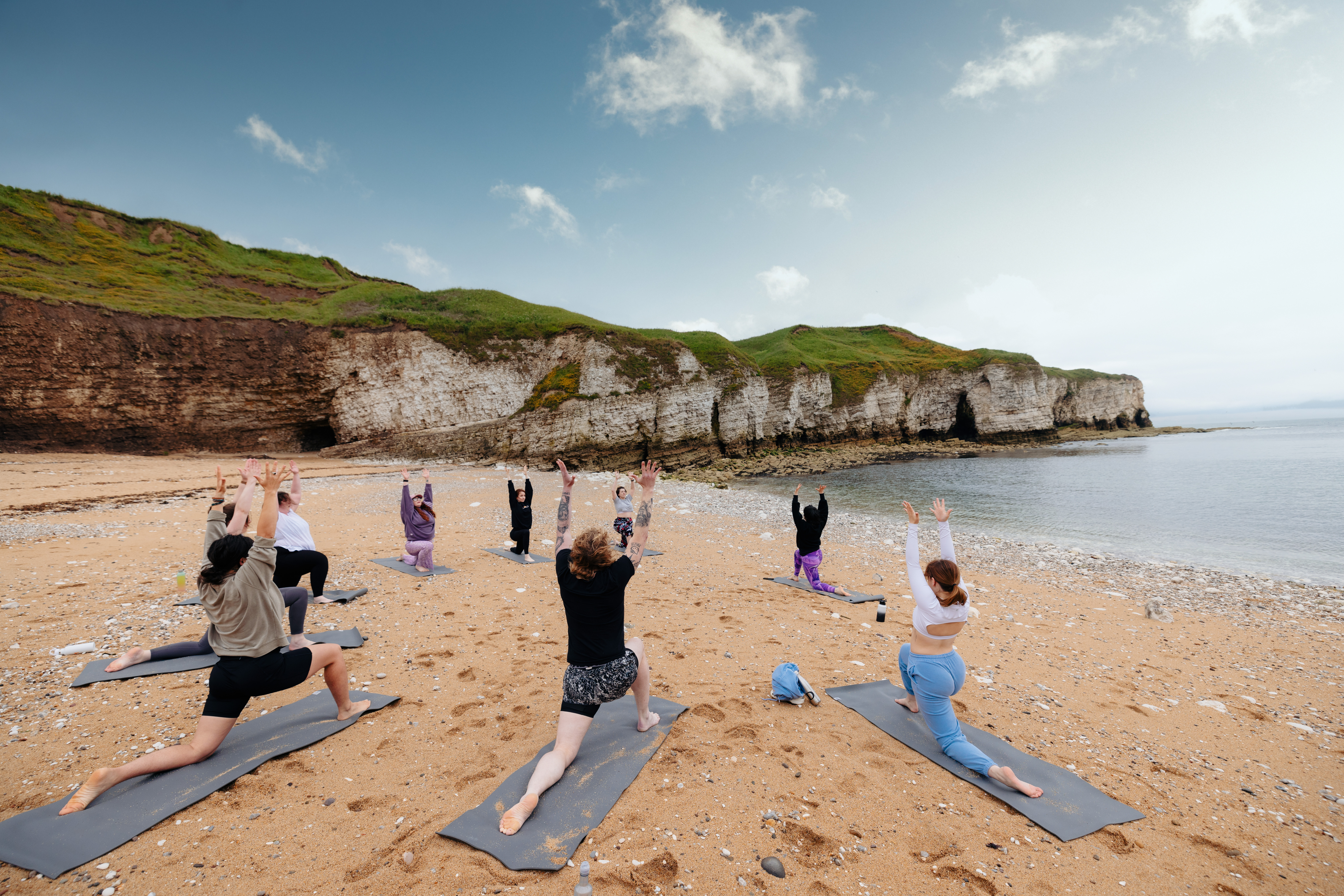 A group of people practising yoga on a beach