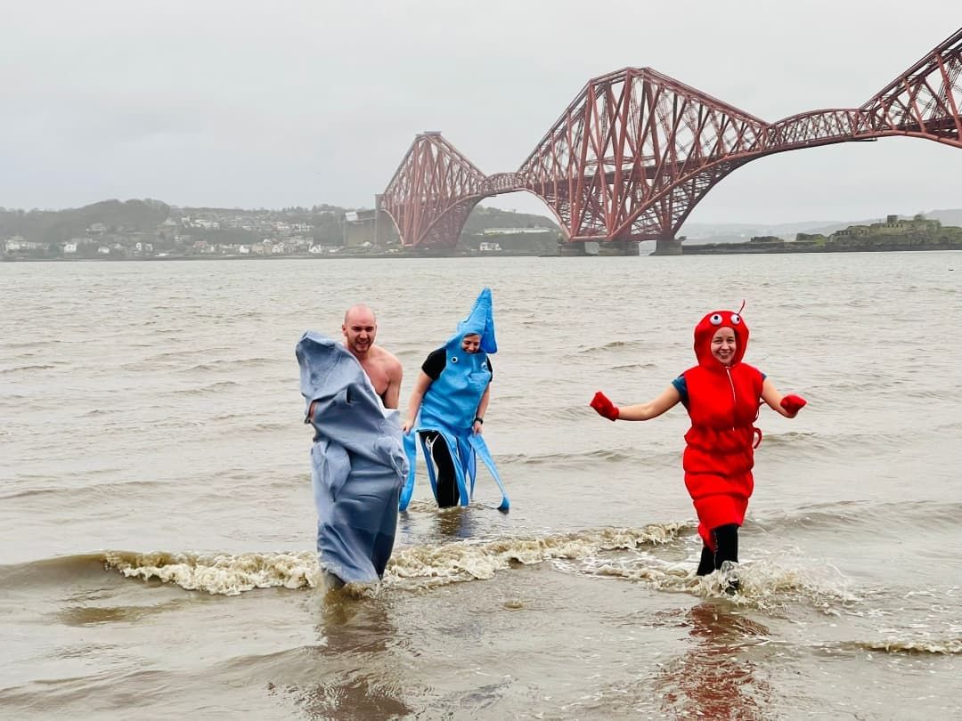 Un groupe de personnes déguisées en calmars sortant de l'eau près de South Queensferry