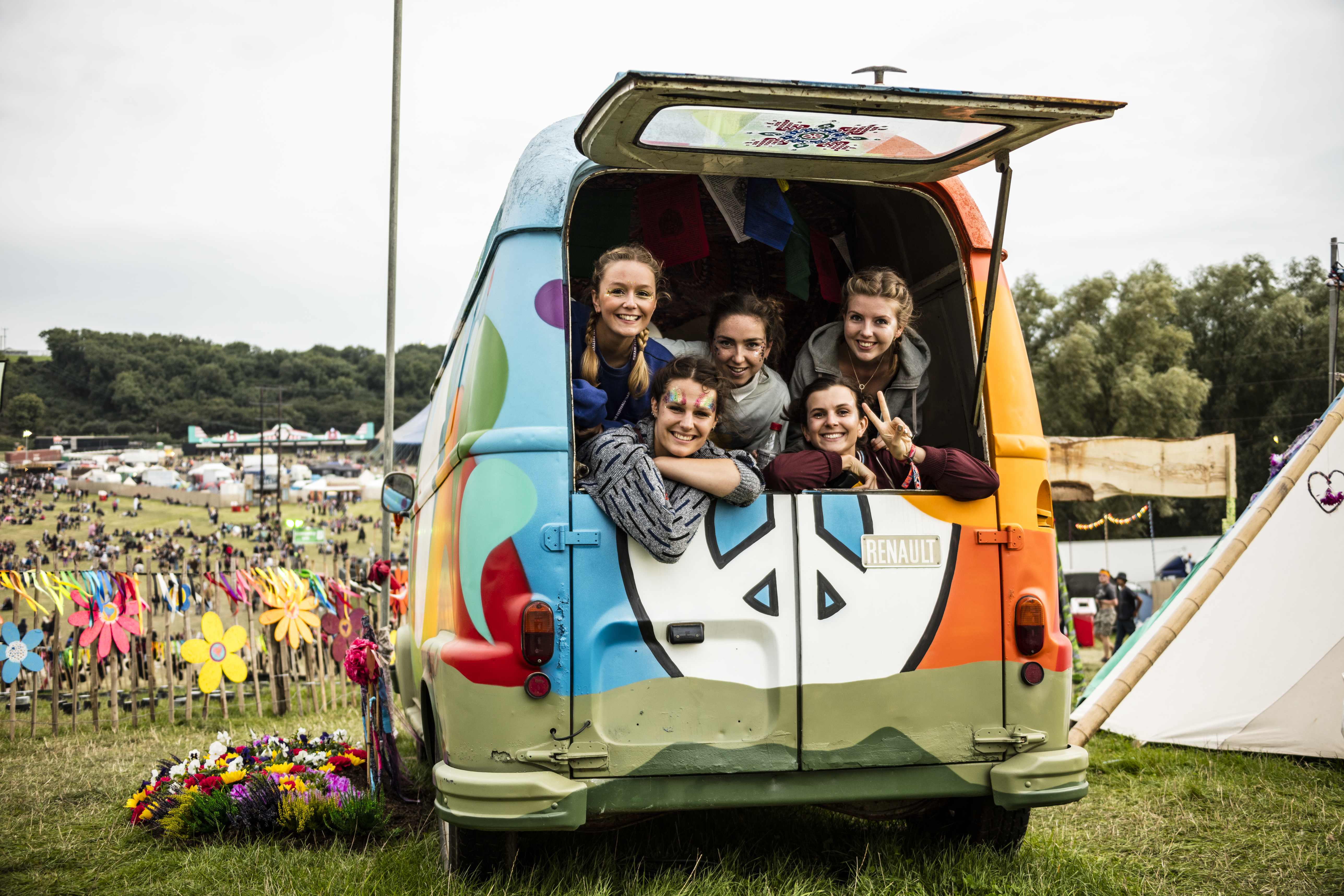 Group of friends smiling out of the back of a rainbow van