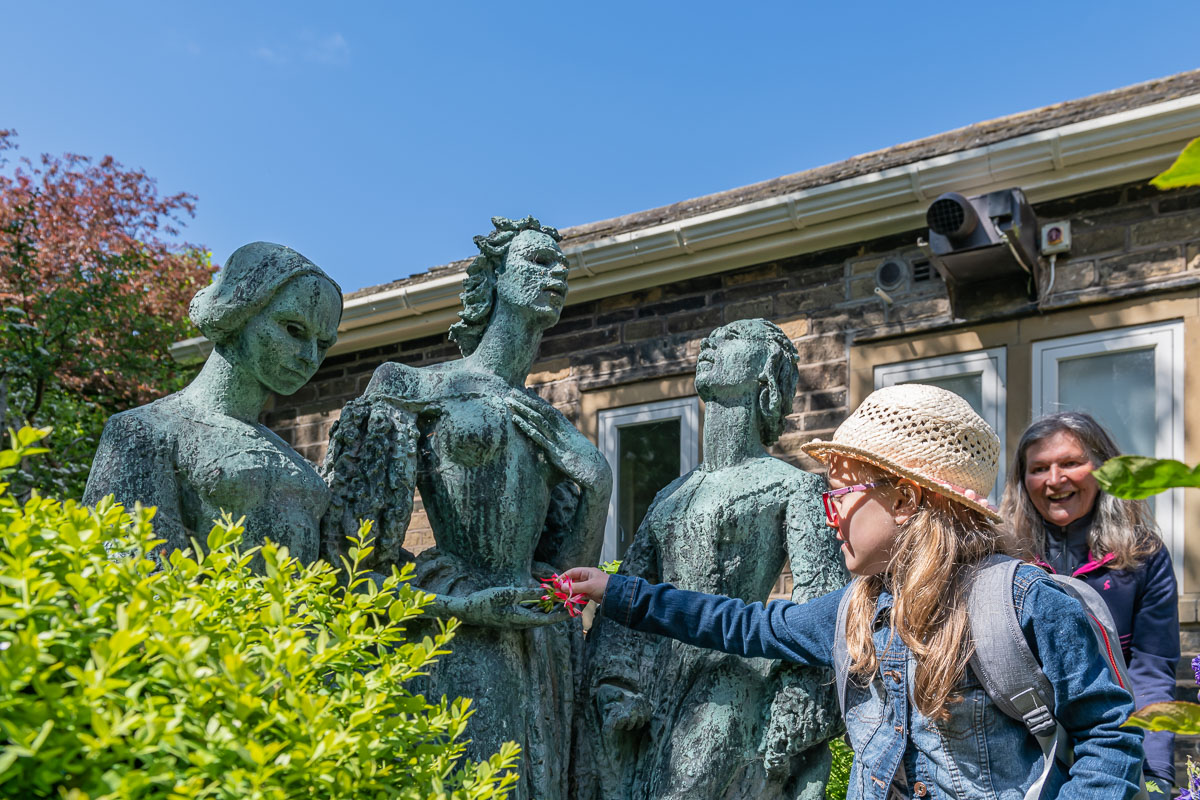 A girl putting flowers into the hands of a statue