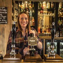 Woman serving drinks behind the bar in a pub