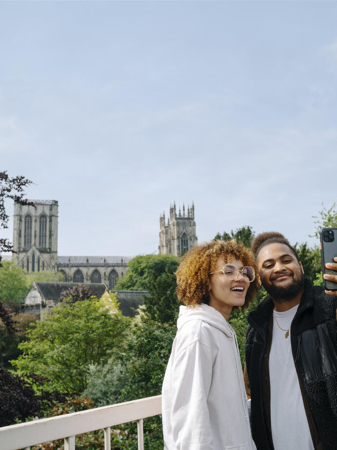 A man and a woman take a selfie in front of a Cathedral view