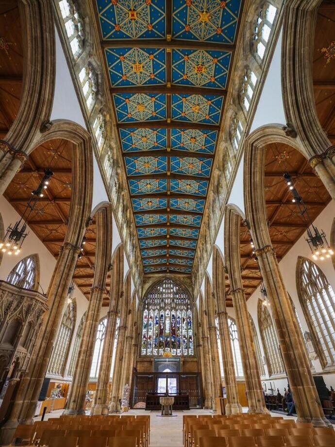 Blick nach oben auf die aufwendig verzierte Decke einer alten Kirche.