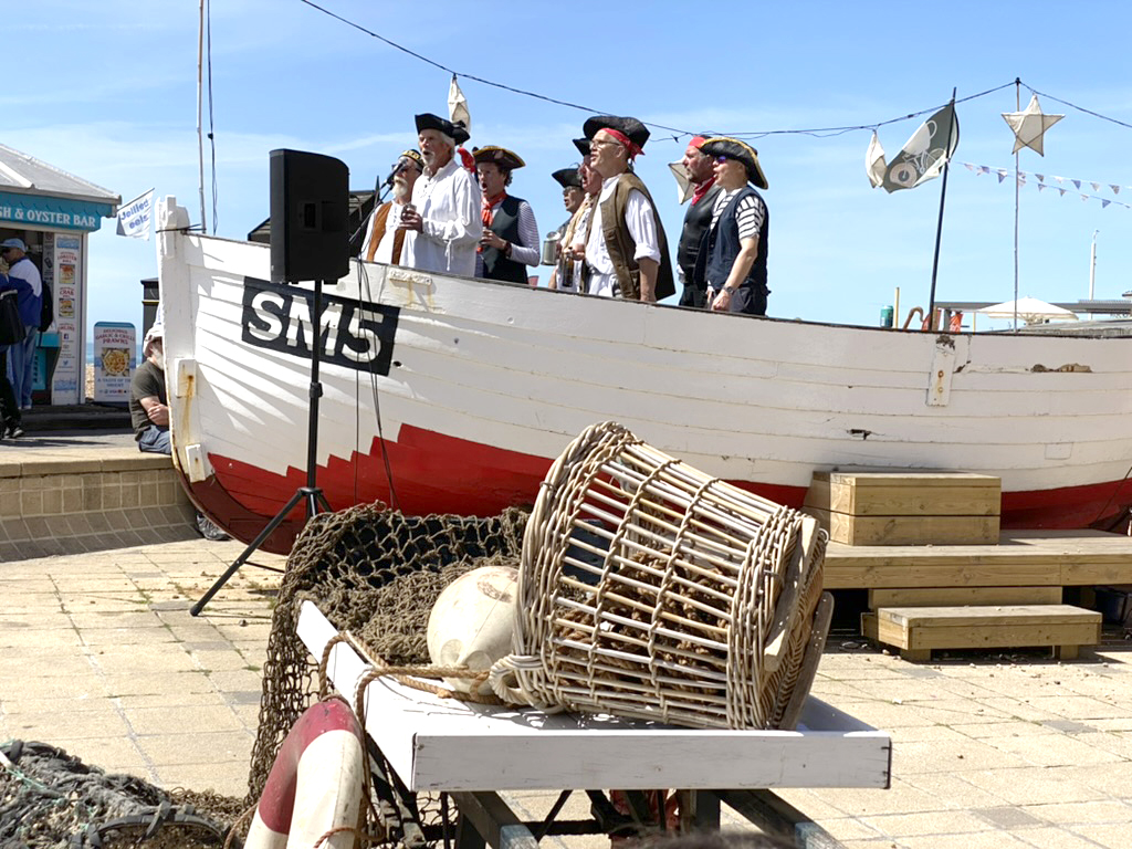 A group of singers in costume outside the Brighton Fishing Museum