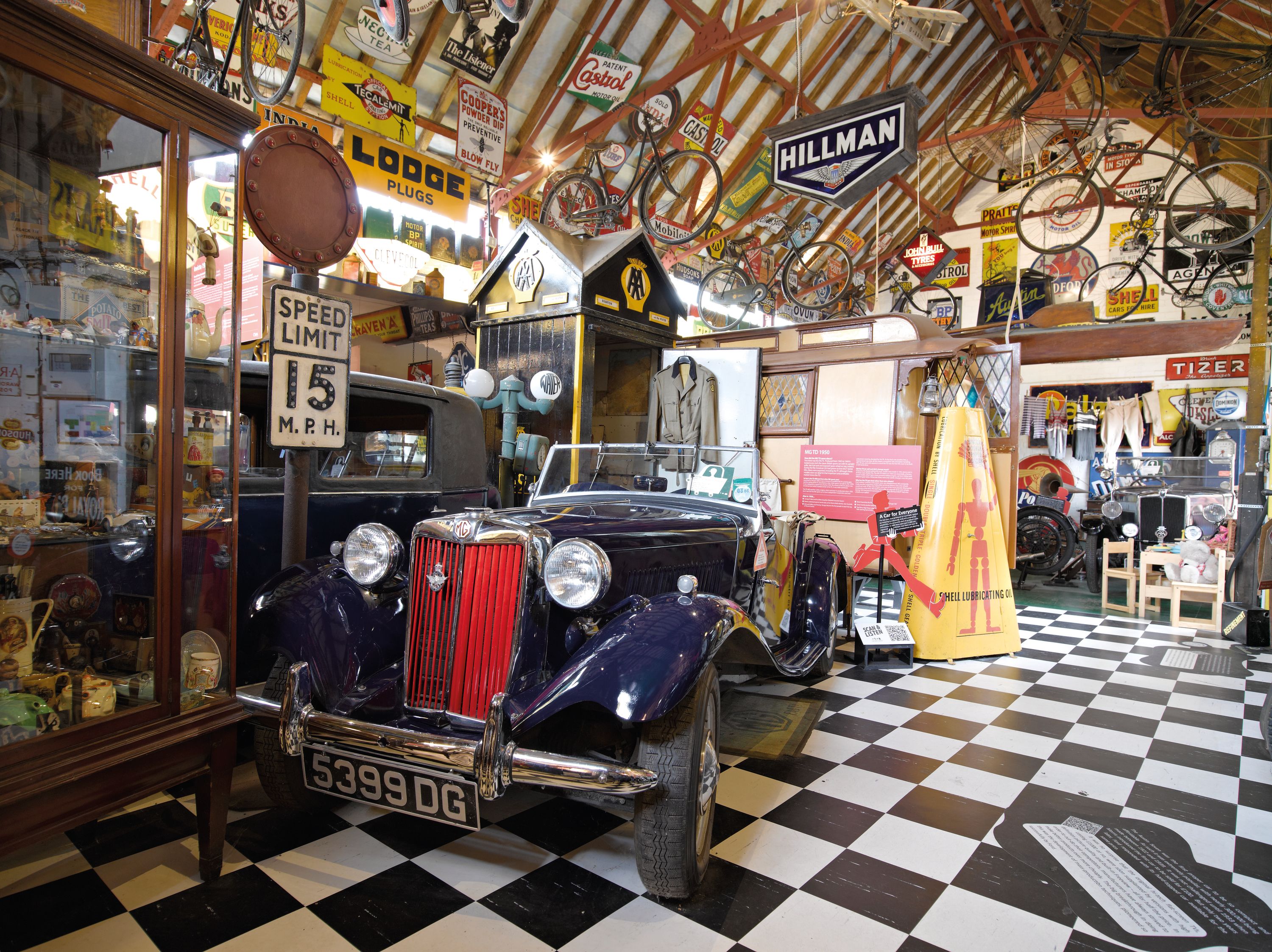 Auto d'epoca, biciclette e cartelli esposti in un museo