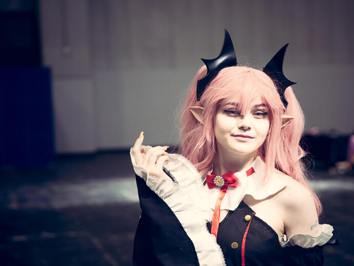 A female cosplayer dressed as a Japanese Anime character with colourful wig and make up at a comic con event
