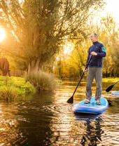 Two people paddleboarding down the River Bure