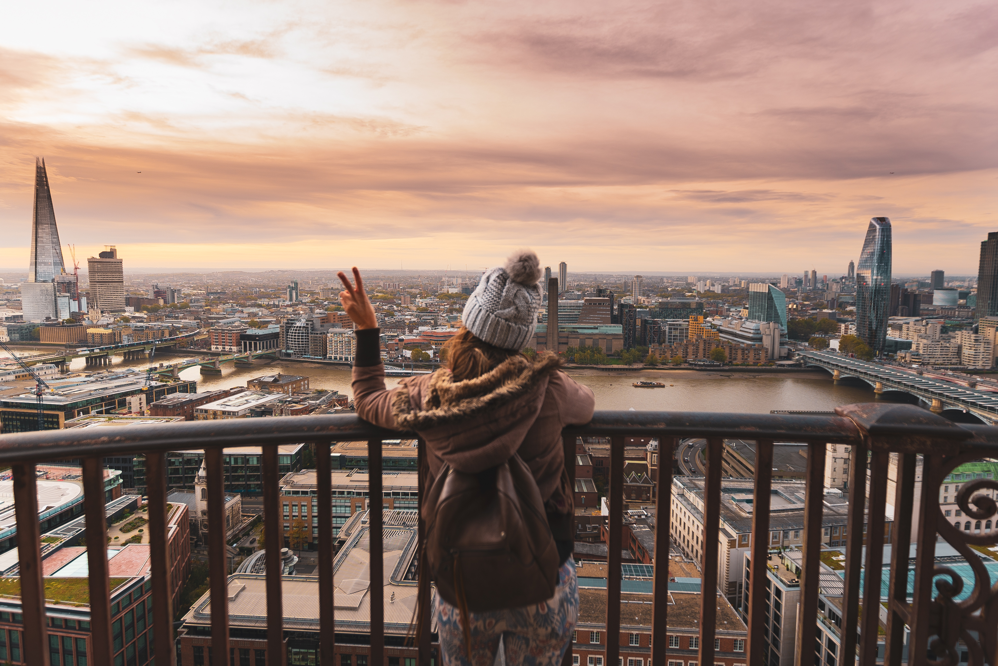 Woman on a balcony at the top of a high building looking over a city