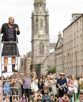 El artista callejero Peter Anderson hace malabares con espadas frente a una multitud en la Royal Mile, Edimburgo, durante el Festival Fringe 2022.