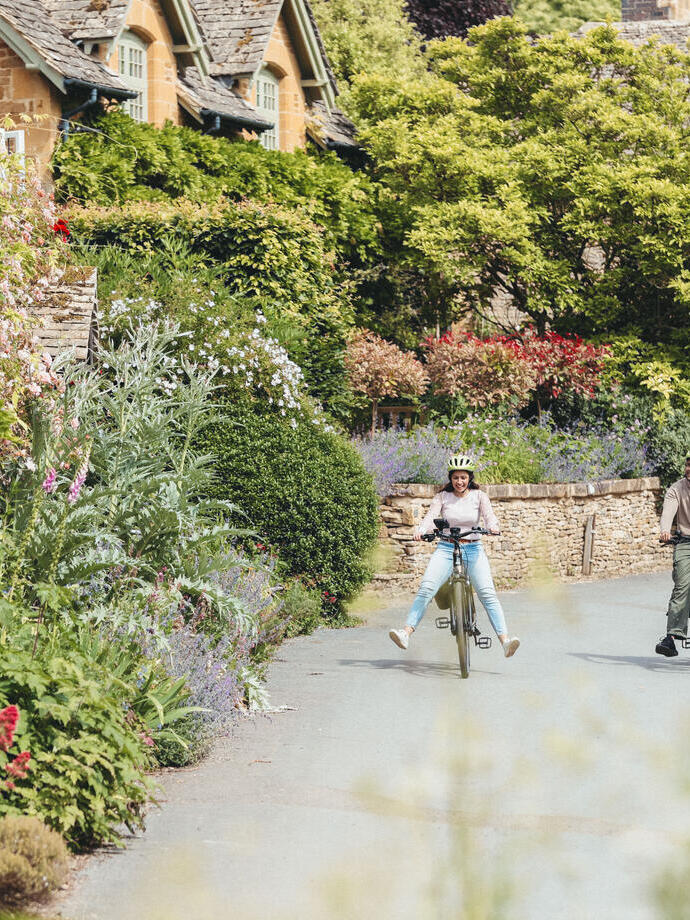 A man and and woman cycle through a quaint village