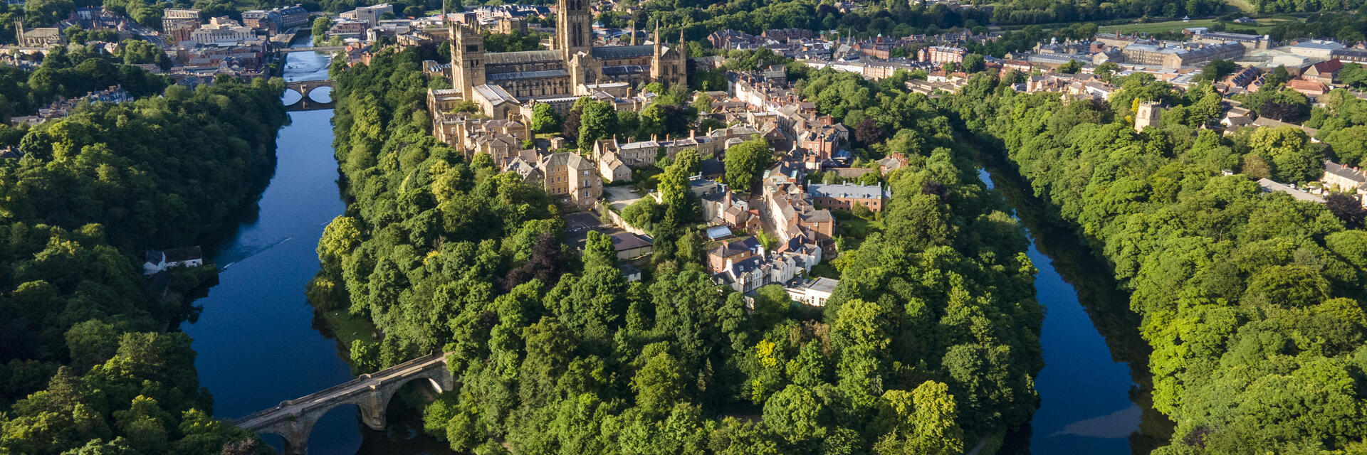 An elevated view of a Cathedral set amongst trees and a river