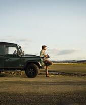 Man leaning against a vehicle, holding camera