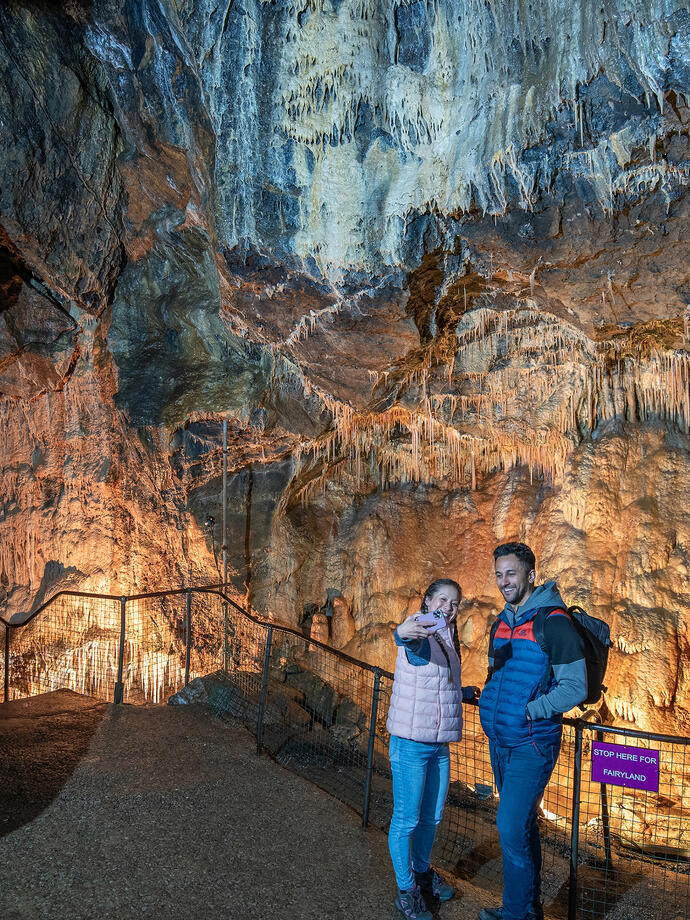 A man and a woman take a selfie with a phone in a cavern