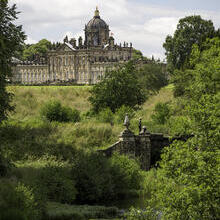 Large country house surrounded by trees with stream in the foreground