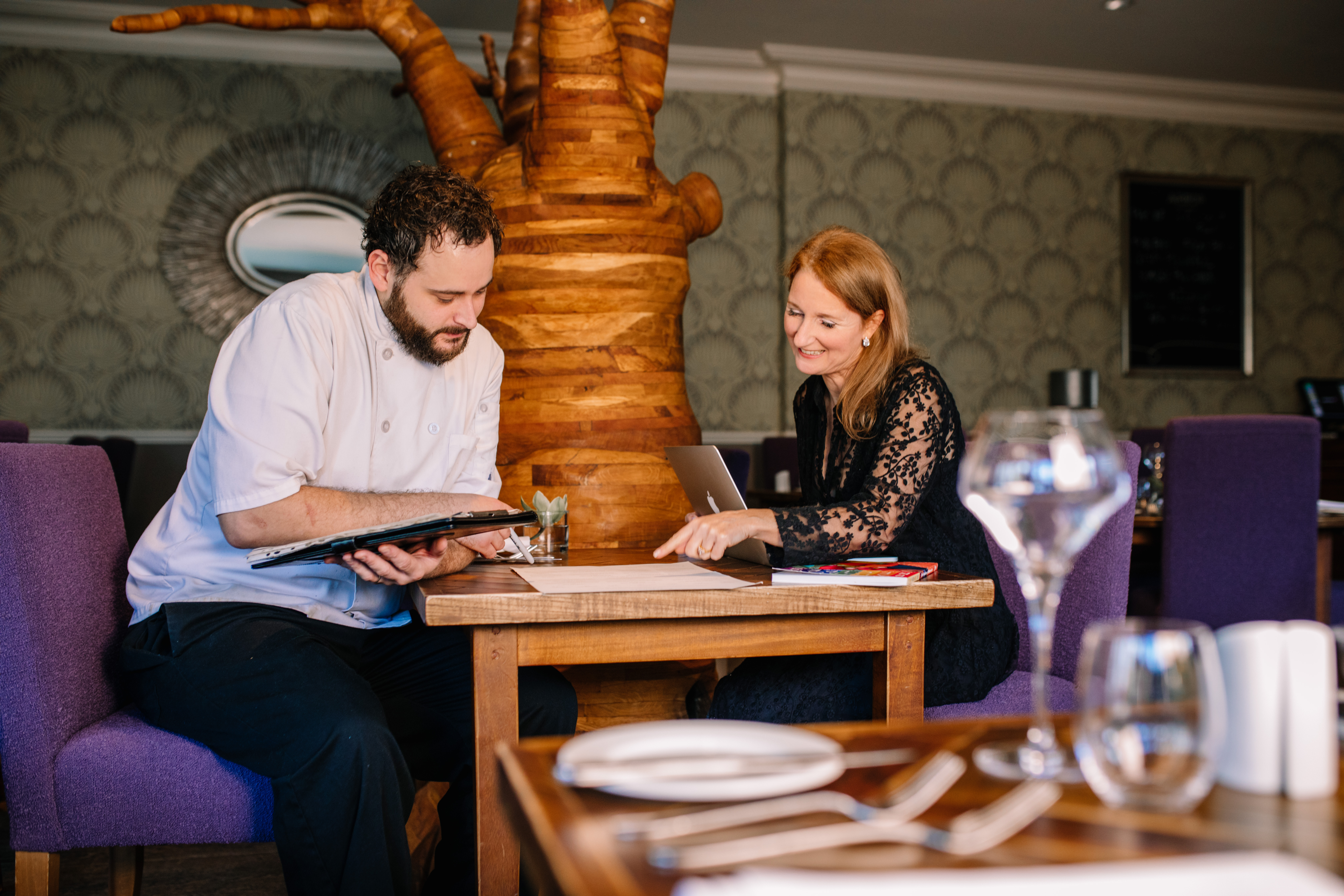 Head Chef and female nutritionalist sat in empty restaurant discussing menu plans for The Green House Hotel, Bournemouth
