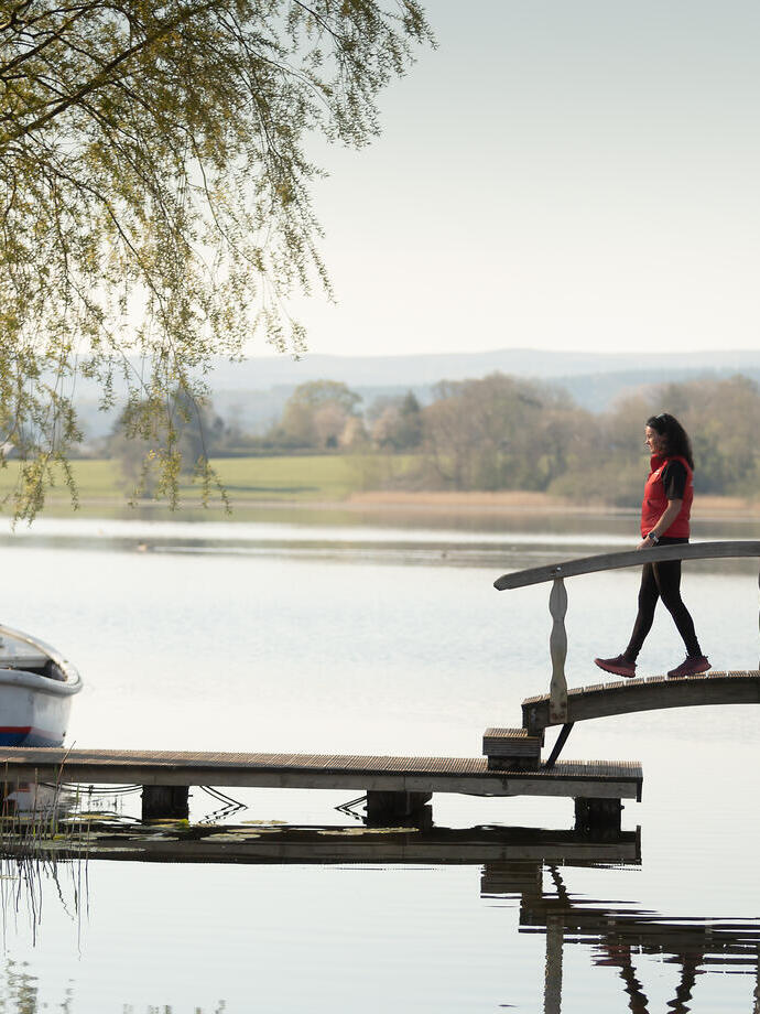 Une femme enjambe un pont, près d'un bateau amarré.