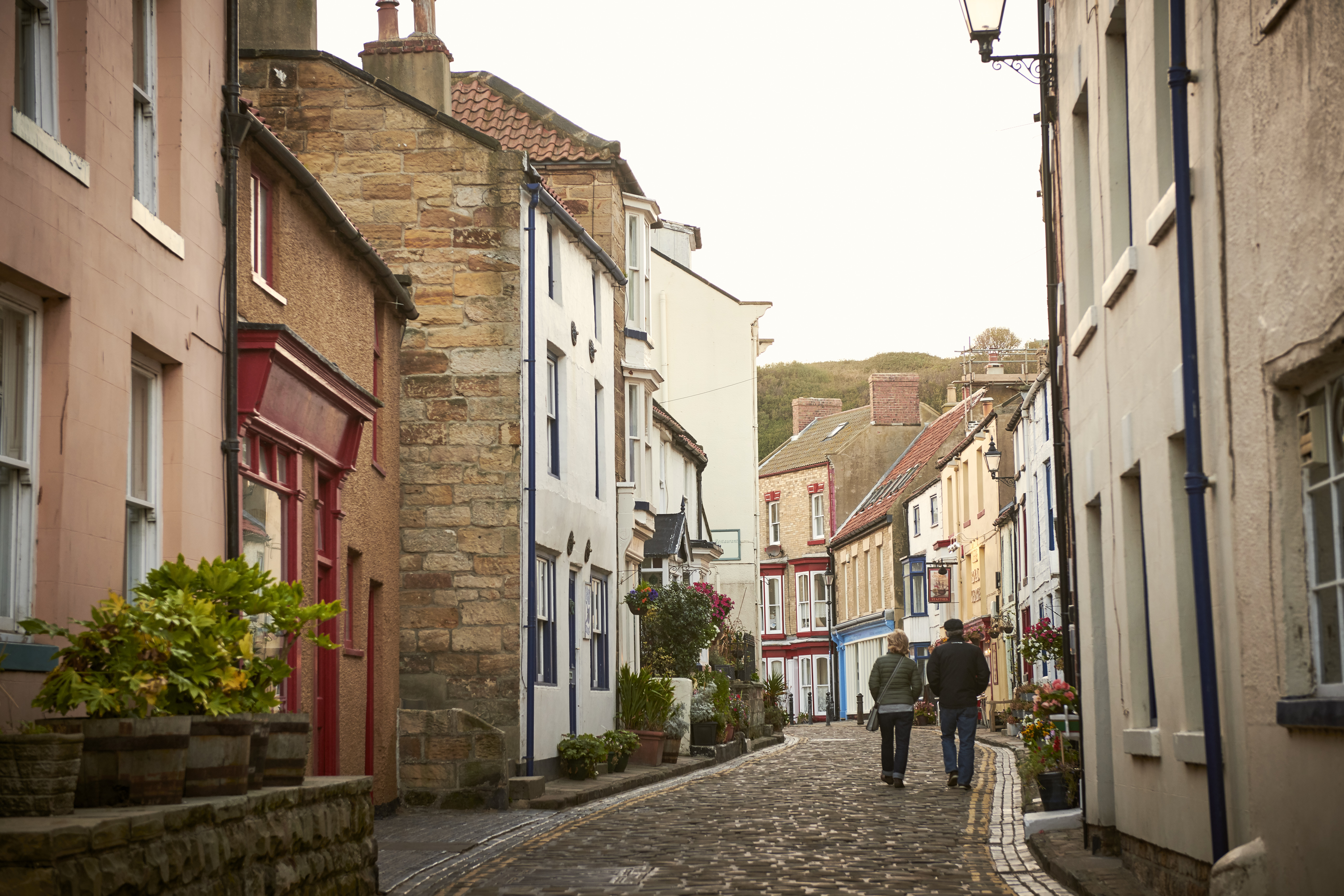 Two people walking down a cobbled village lane