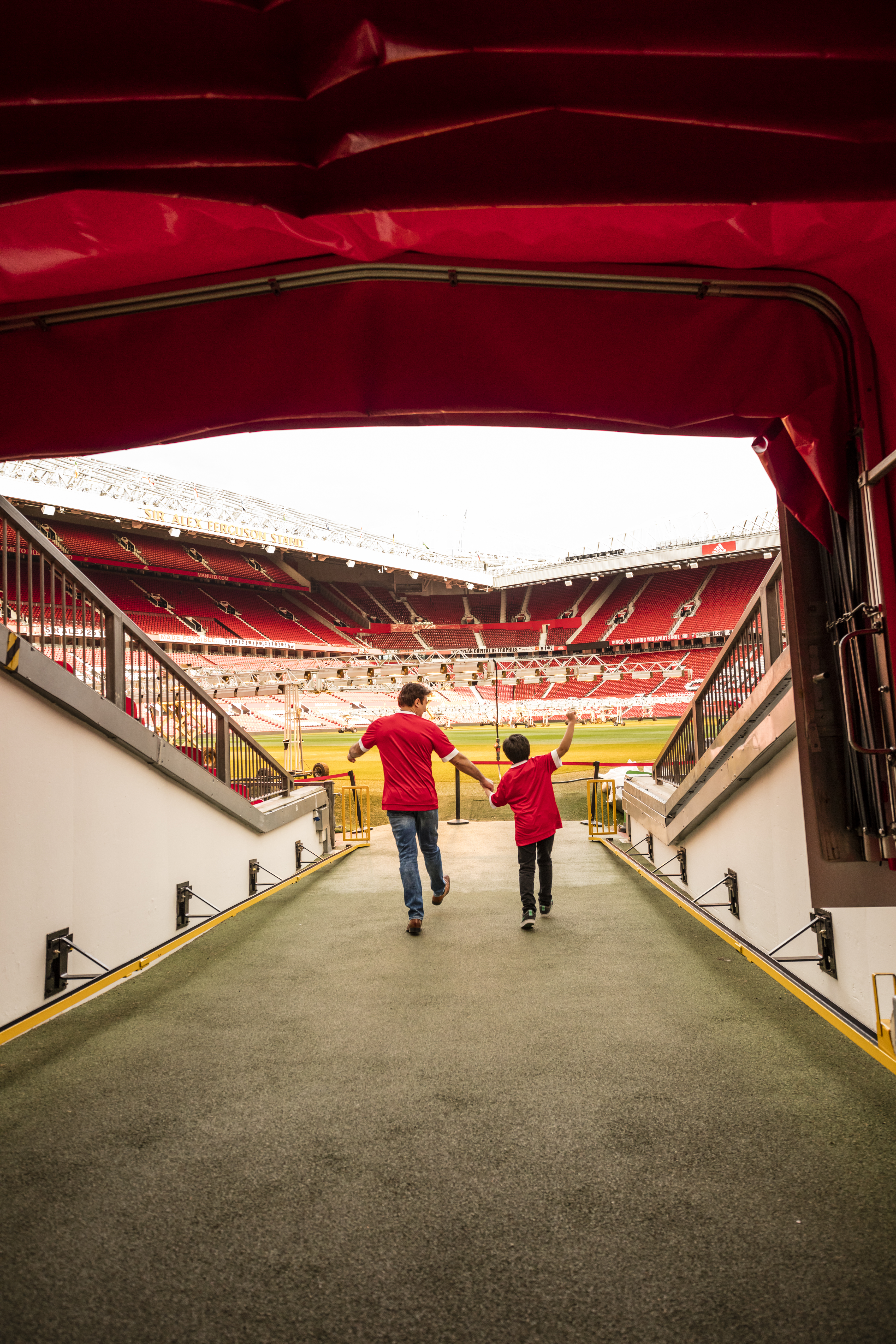 Un hombre y un niño en el túnel del estadio mirando hacia el campo