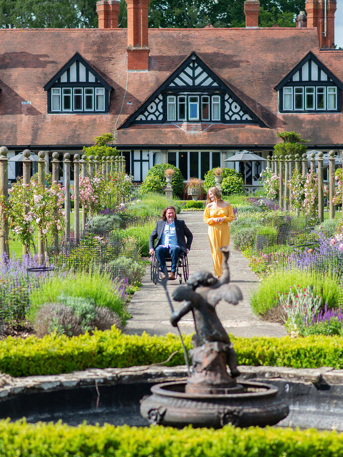 A woman and a man in a wheelchair smiling together in summer gardens