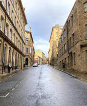 Vista de una carretera desierta, bordeada de edificios victorianos de piedra.