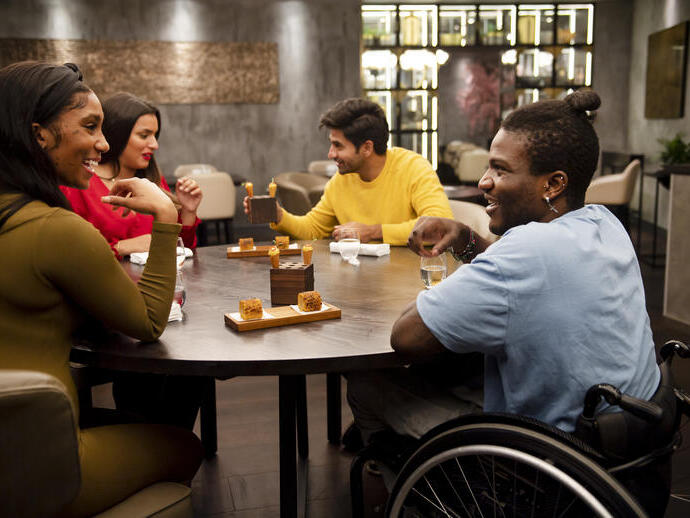 Groupe d'amis, dont une personne en fauteuil roulant, assis à une table dans un restaurant