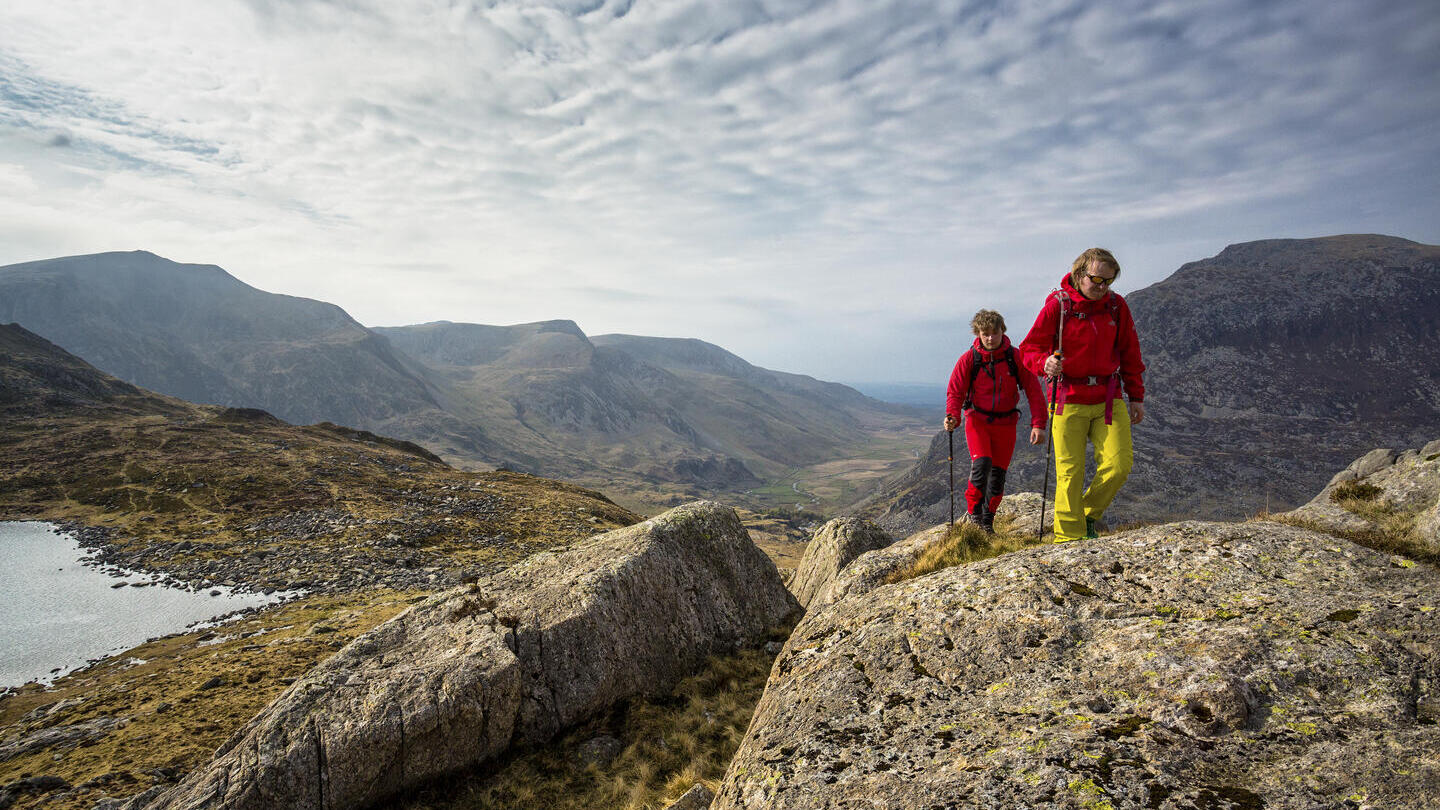 Two people walking to the high pass through the mountains