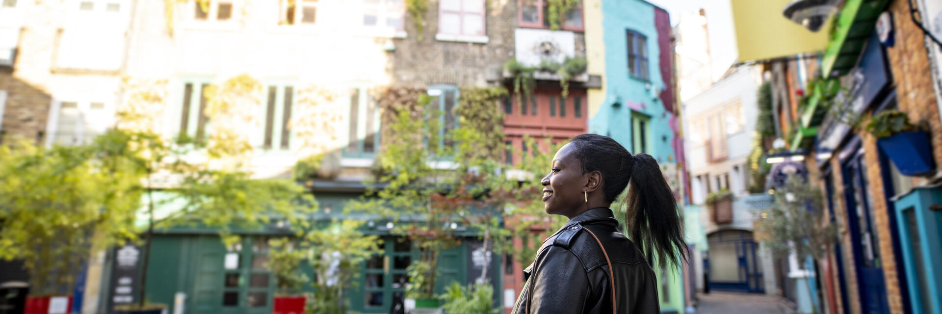 Female tourist exploring a London shopping courtyard with shops and outdoor seating.