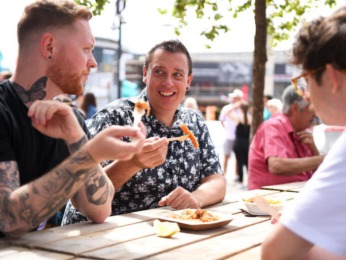 Un grupo de hombres comiendo en una mesa en el Festival Internacional de Comida y Bebida en Cardiff, Gales