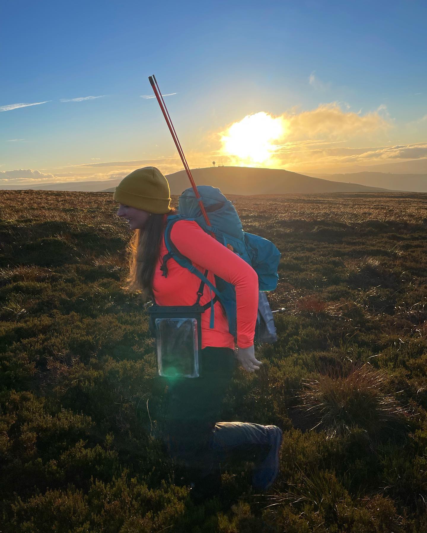 متنزهة تحمل حقيبة ظهر وعصي المشي، تتنزه في ريف كيلدر في نورثمبرلاند عند شروق الشمس