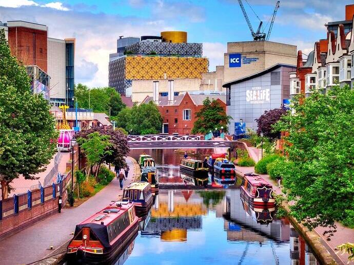 Canal boats on a canal in a city surrounded by homes and buildings