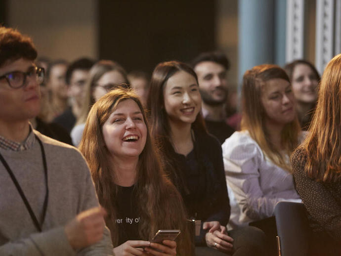 Group of people sat at event, smiling