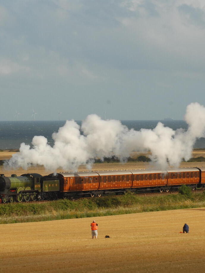 A steam train passing through fields on the coast