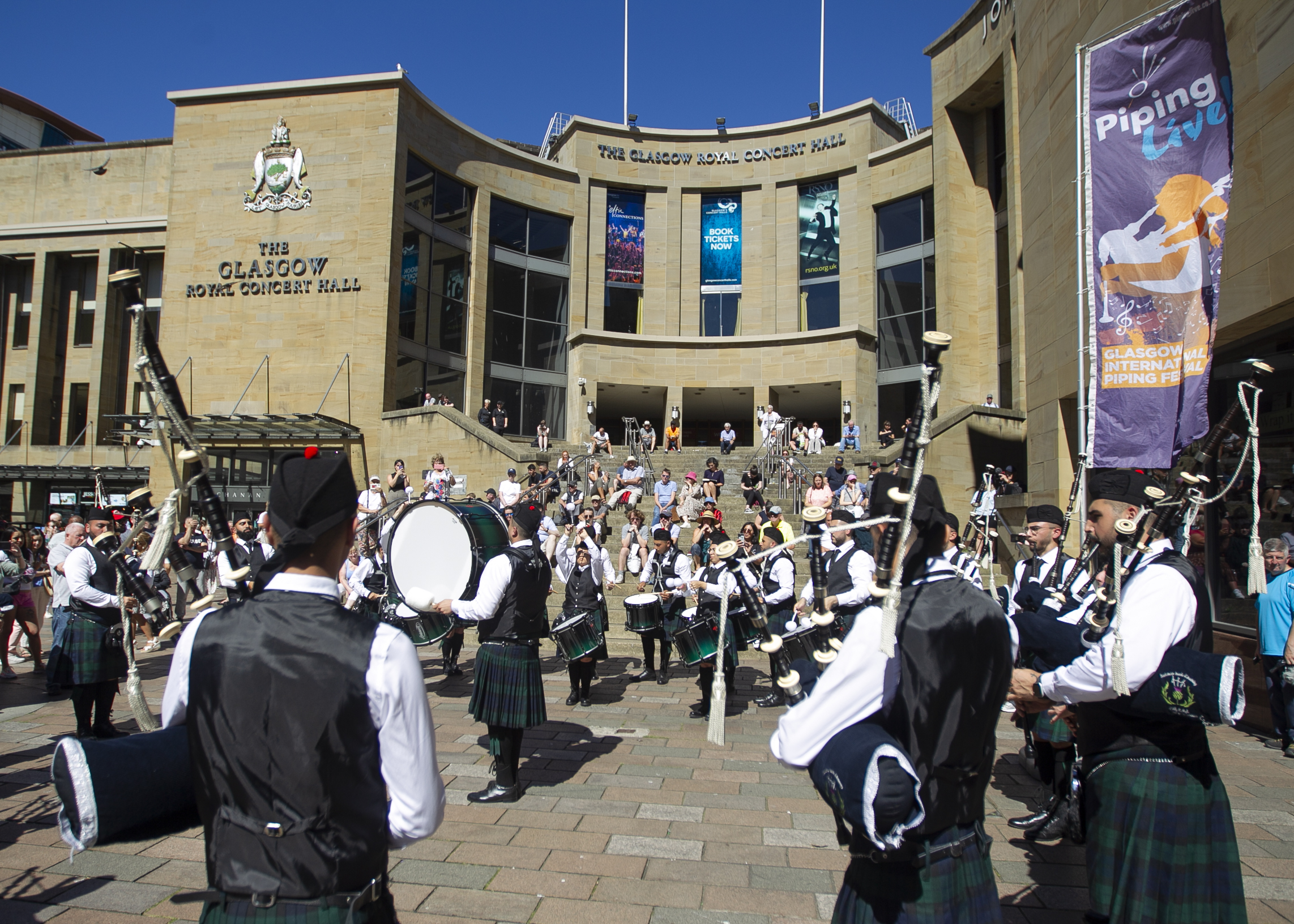 Piping band with drums play for the crowds outside The Glasgow Royal Concert Hall.