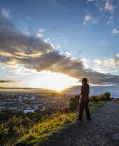Man enjoying panoramic views of Edinburgh at the top of Arthur's Seat