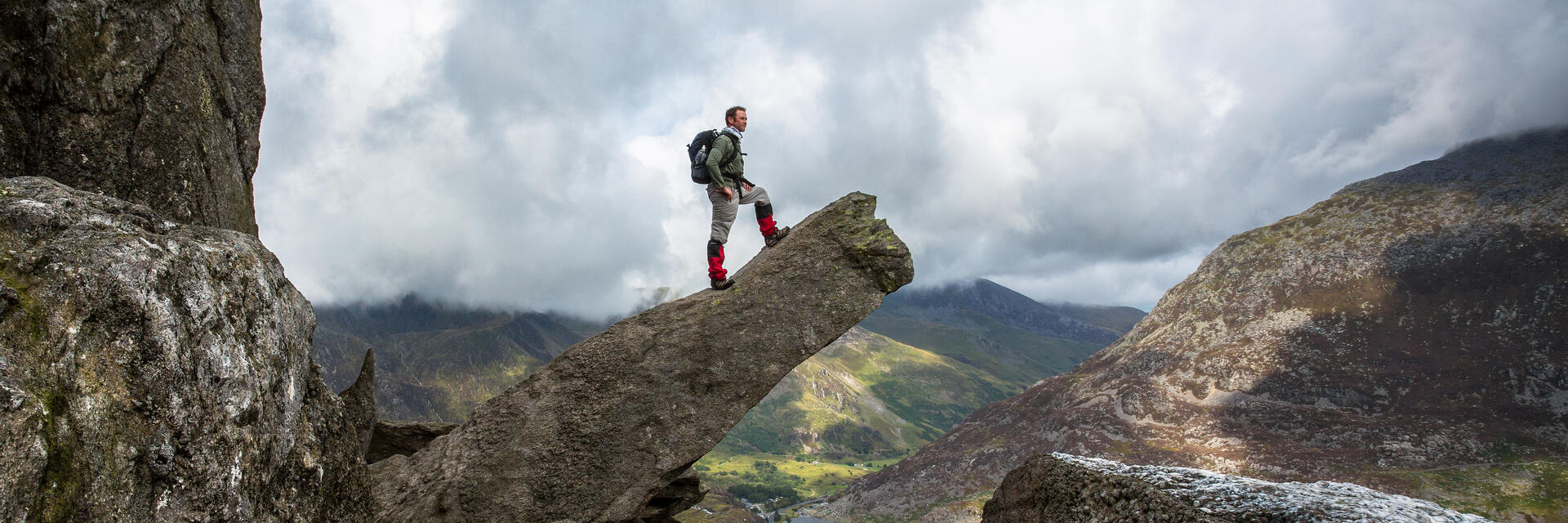 Mann, der auf einer hervorstehenden Felsformation steht und die Aussicht betrachtet