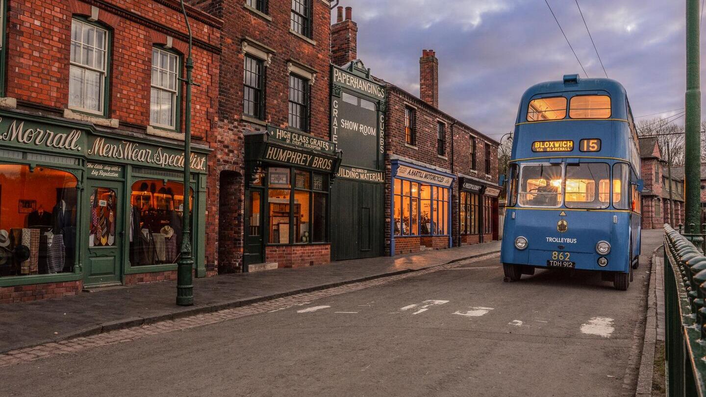 Un bus bleu vintage circulant dans une rue d'un musée vivant