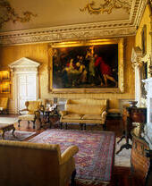 Un salon somptueux dans une demeure seigneuriale avec des murs jaunes, un tapis rouge et d'autres équipements luxueux.