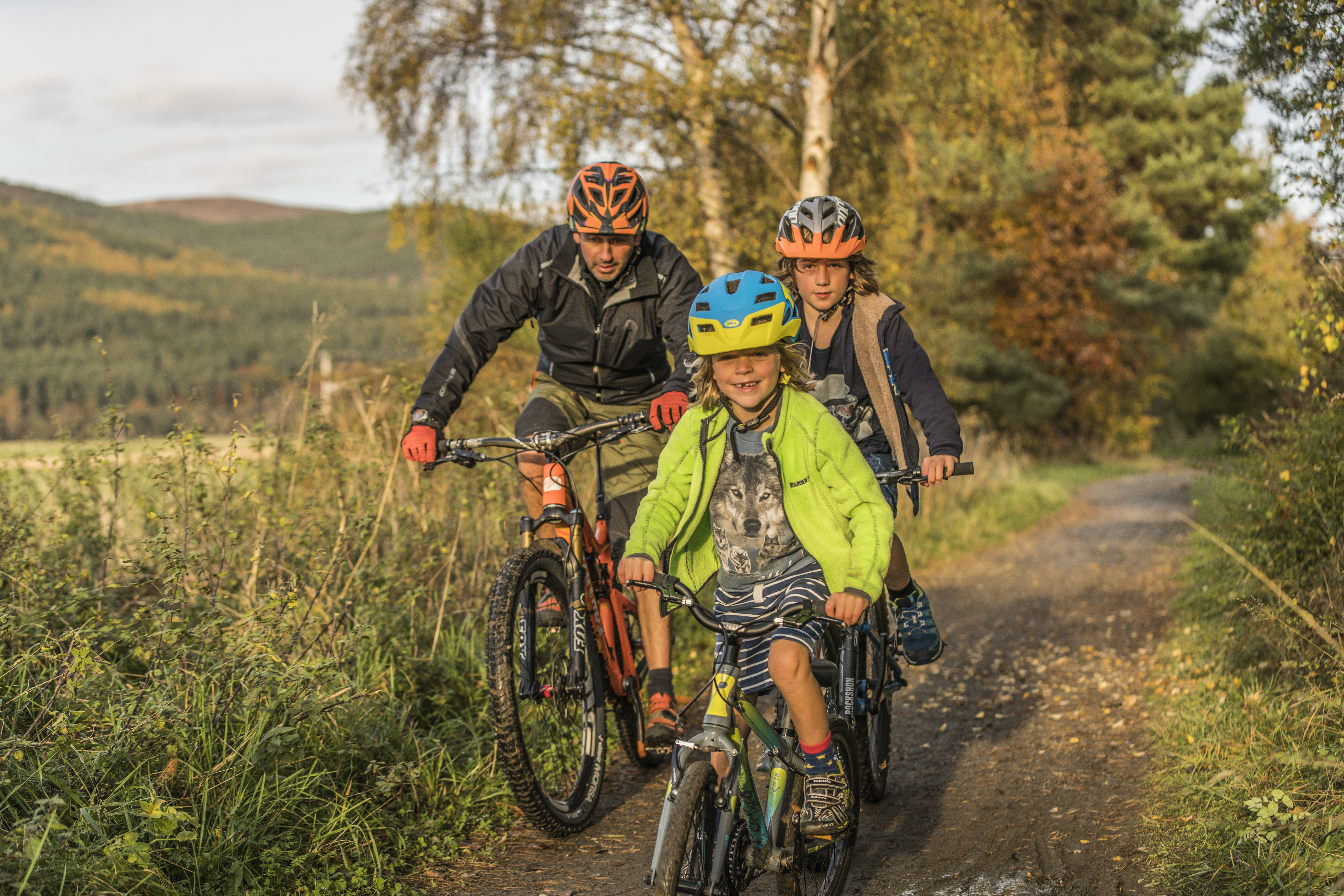 Adult and two children cycling on a path through the countryside